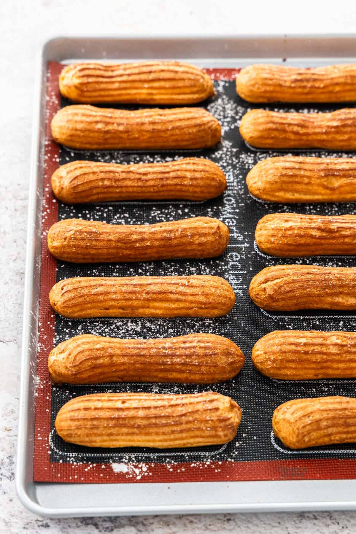 A baking sheet with baked eclairs lined up.