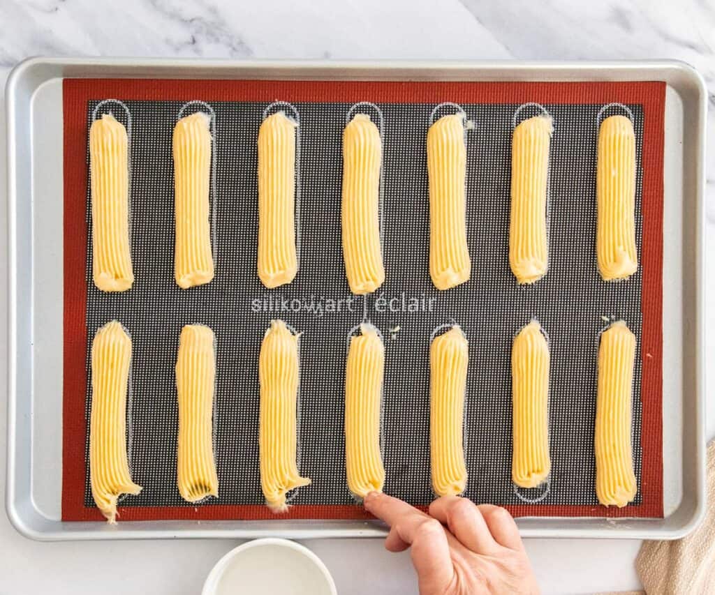 A finger touching up the untidy ends of the eclairs.