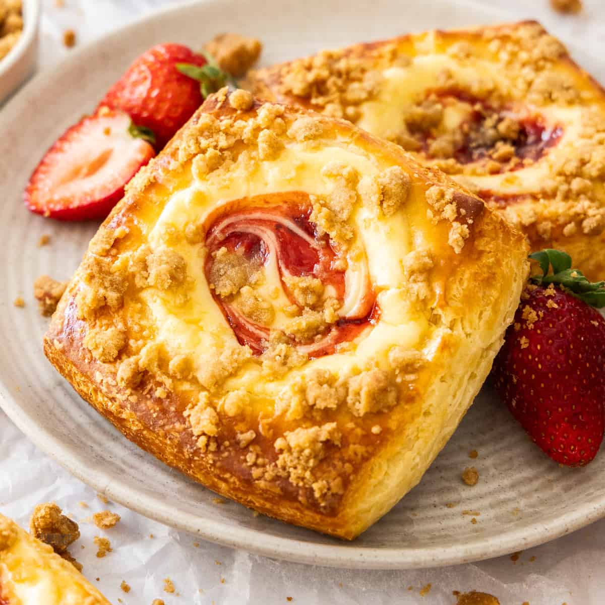 Closeup of 2 strawberry cheesecake Danish pastries on a plate.