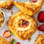 Top down view of strawberry cheesecake Danishes on a sheet of baking paper.