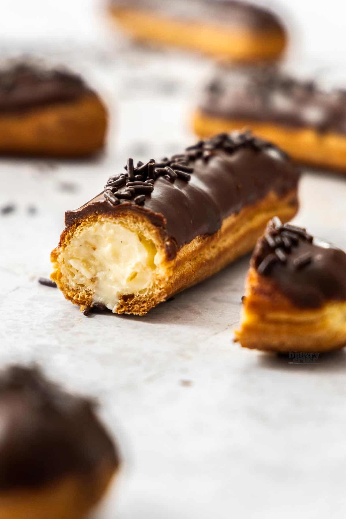 A chocolate eclair cut open to show the filling inside.