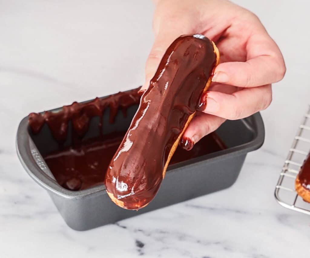 A chocolate eclair that's just been dipped into chocolate glaze.