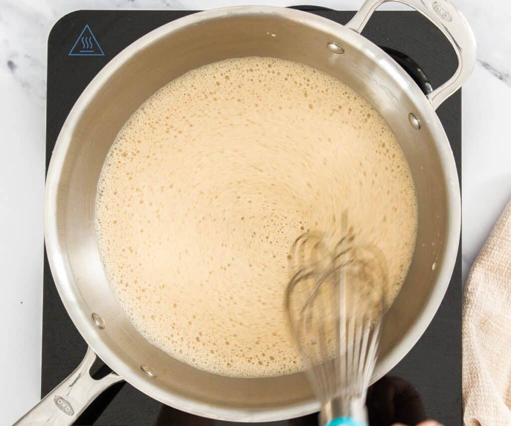 Whisking the mixture, with the coffee powder added, in a saucepan.
