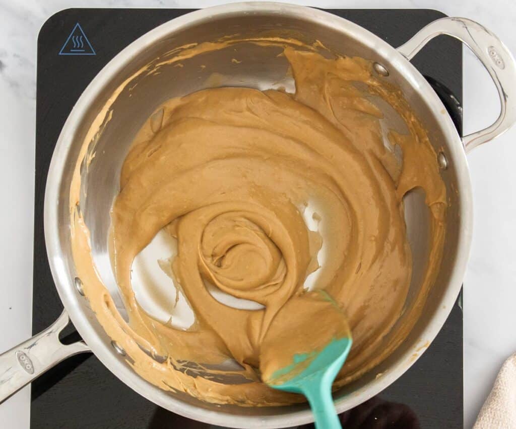 A saucepan with coffee pastry cream showing the thickness.