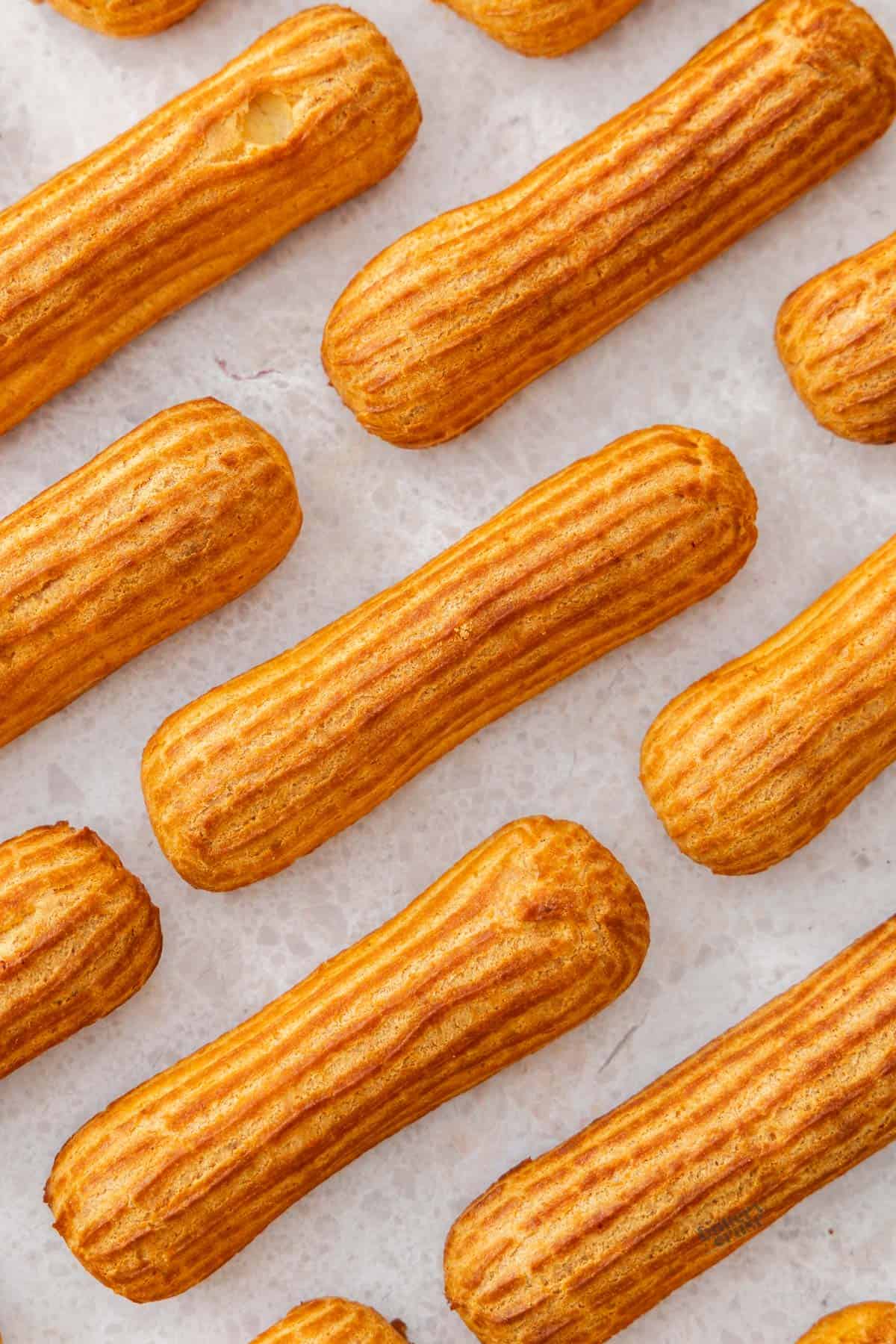 Top down view of eclairs on a stone surface laying on a diagonal in lines.
