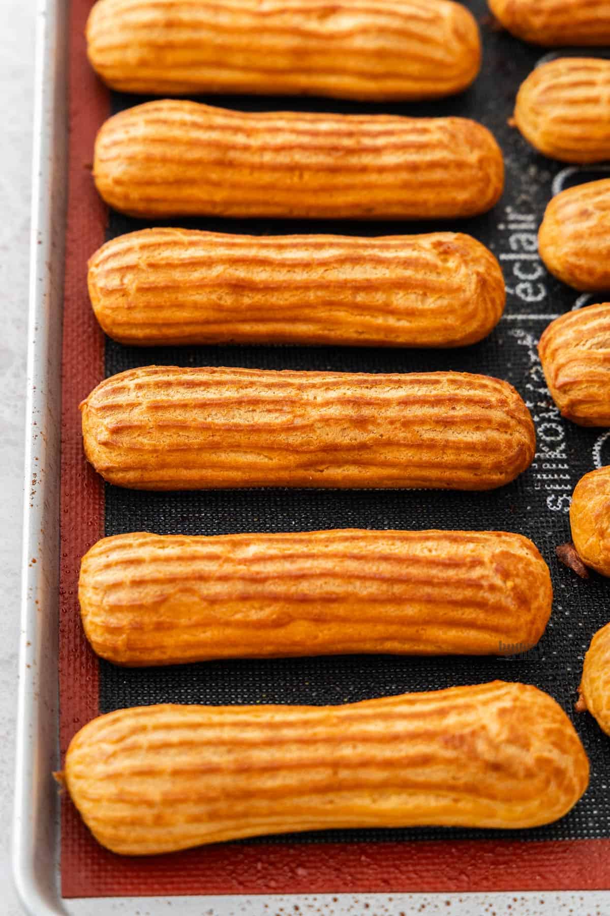 A 45° shot of 6 eclairs on a baking sheet.