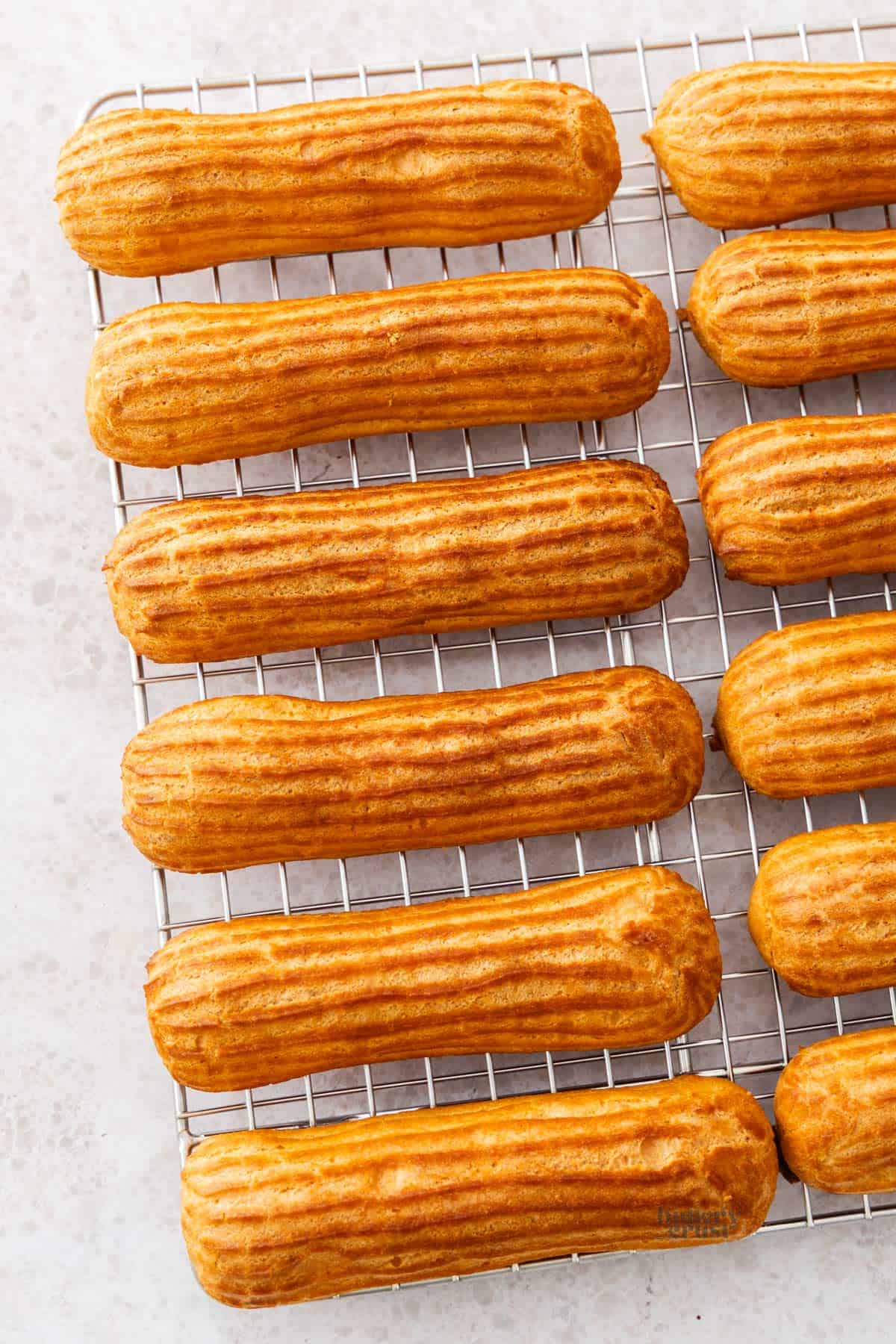 Top down view of 12 eclairs on a wire rack.