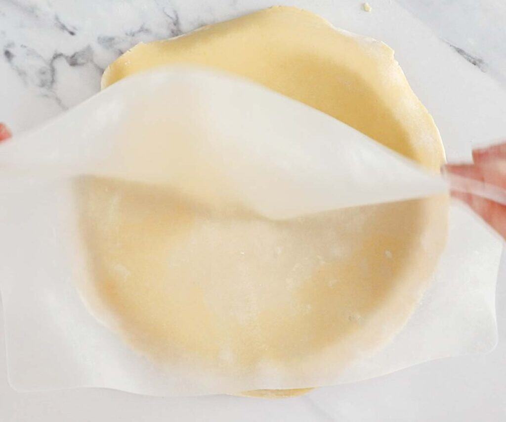 A silicone mat being pulled away from pastry over a tart pan.