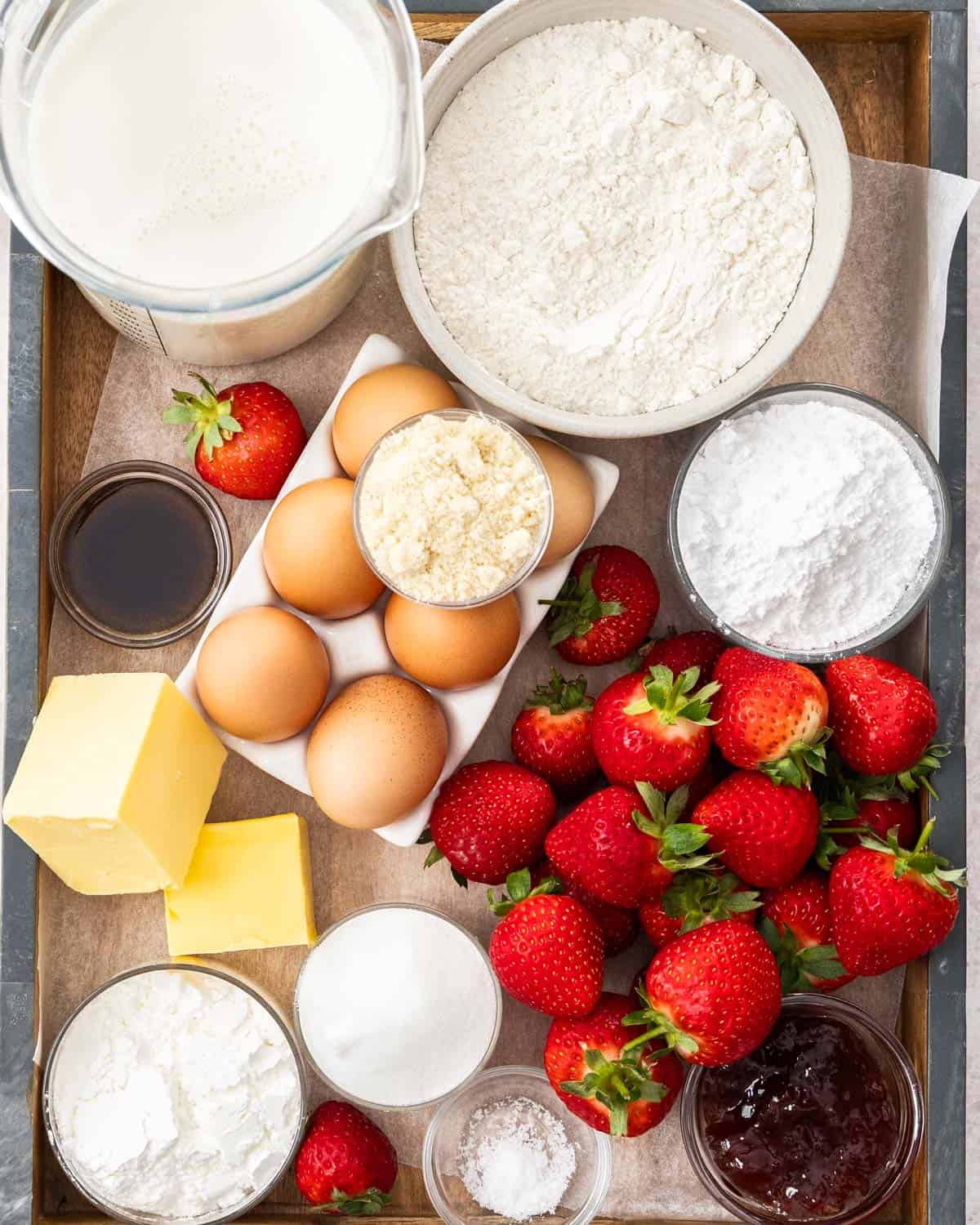 Ingredients for strawberry tart on a wooden tray.