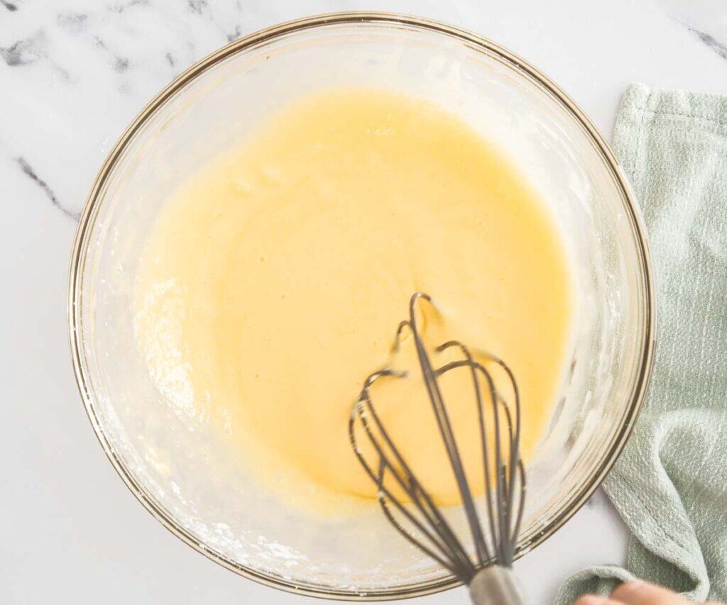 Add hot milk to the egg mixture in a glass bowl.