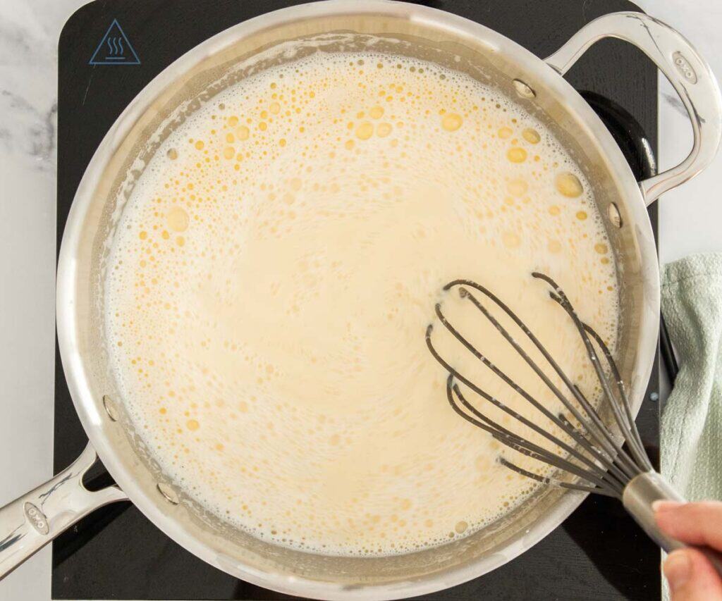 The pastry cream mixture added to the saucepan being whisked while heating.