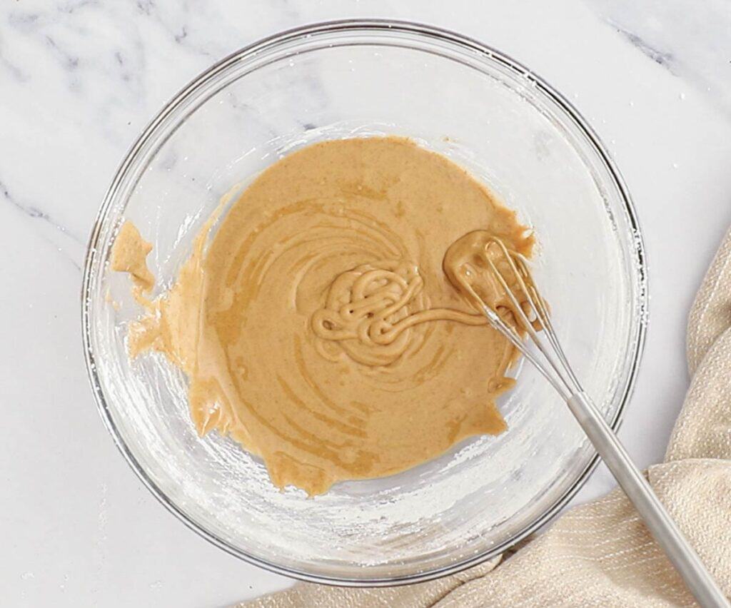 The coffee glaze and a small whisk in a mixing bowl.