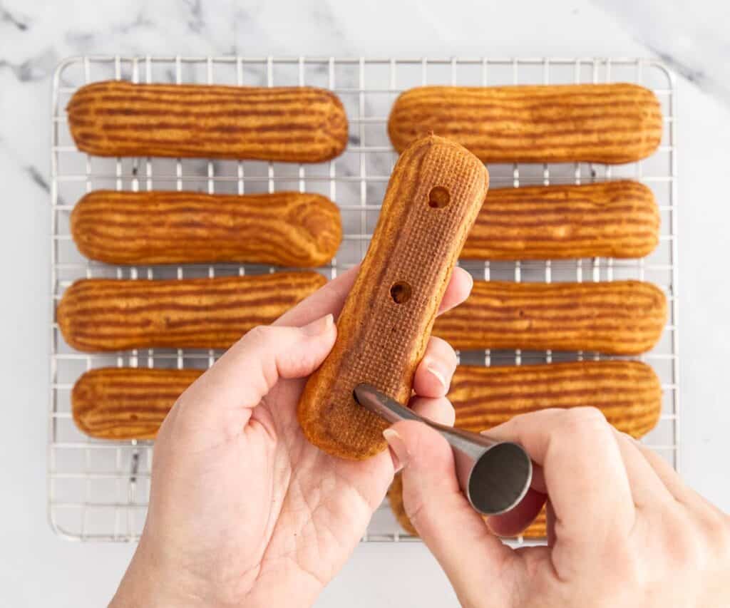 Making holes in the base of eclairs with a Bismarck piping tip.