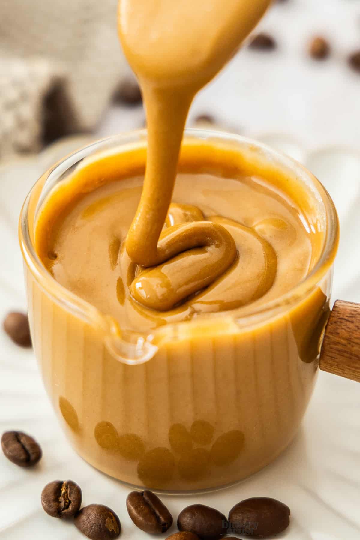 Extreme closeup of coffee glaze being drizzled into a glass.