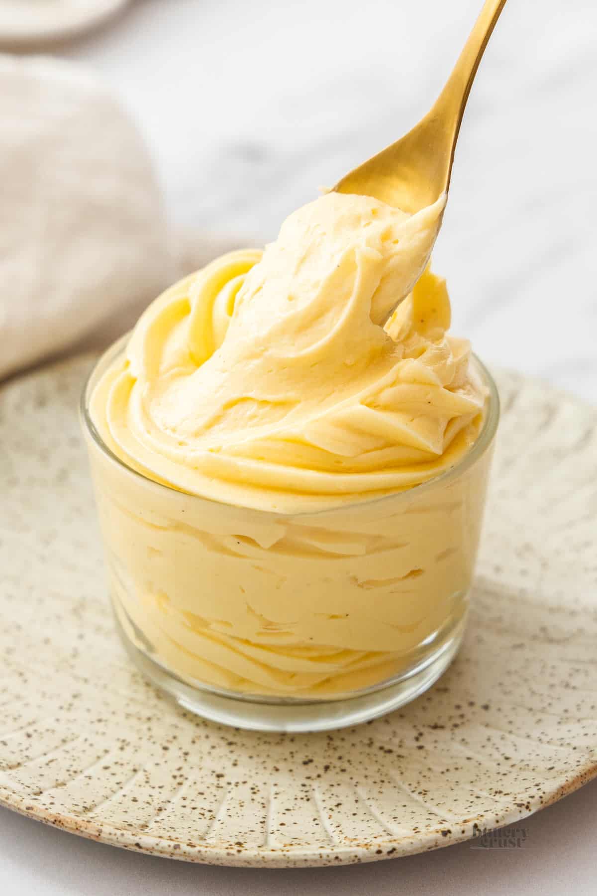 A spoon lifting creme mousseline from a glass.