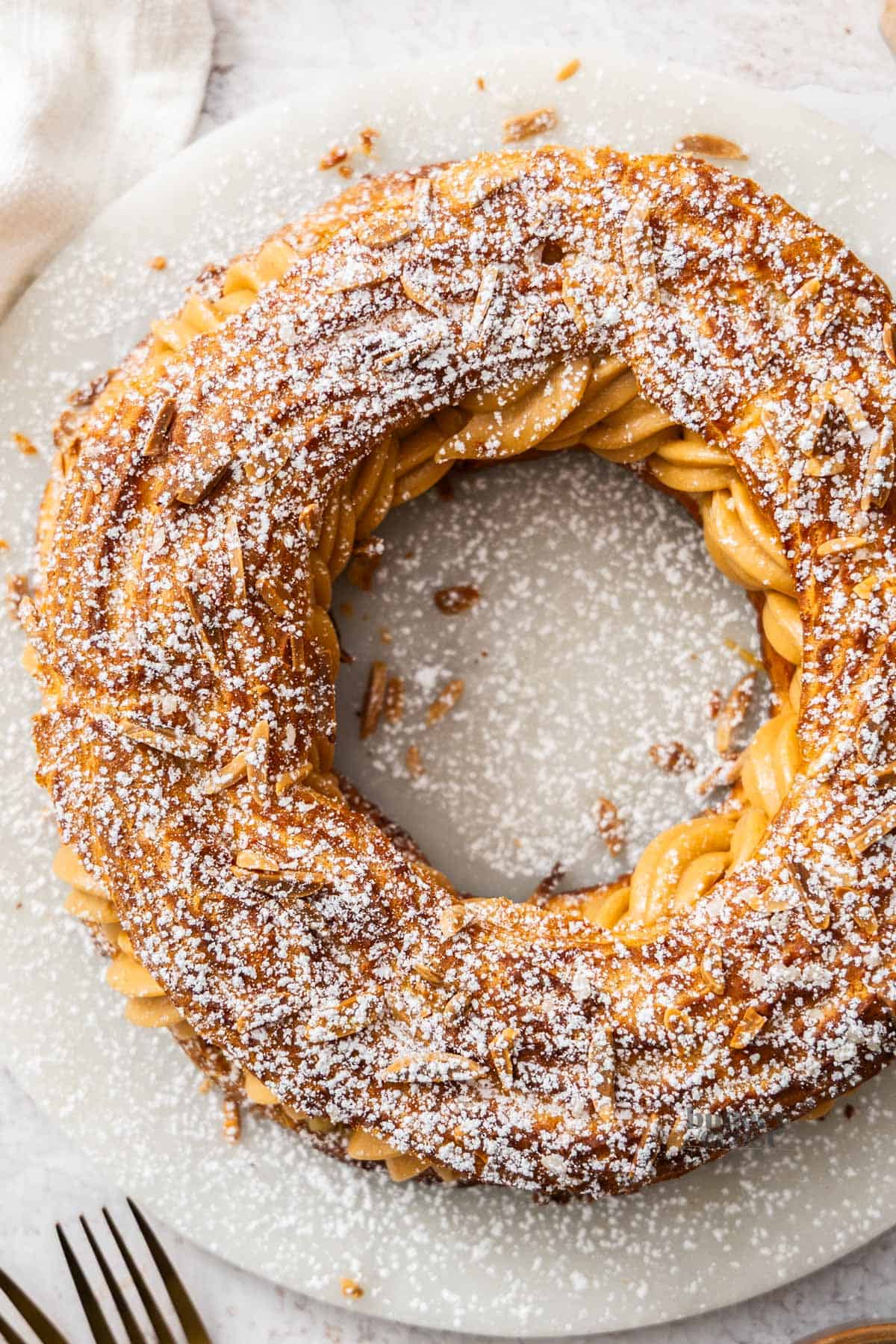 Top down look at a whole Paris brest on a marble platter.