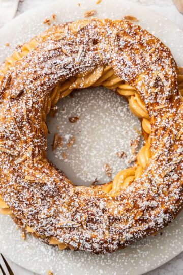 Top down view of a whole Paris Brest on a marble platter.