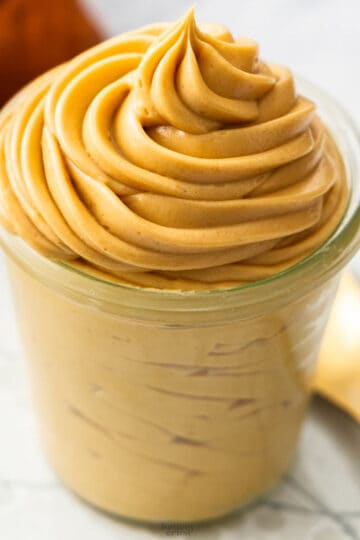 Praline cream piped into a glass jar in a big swirl.