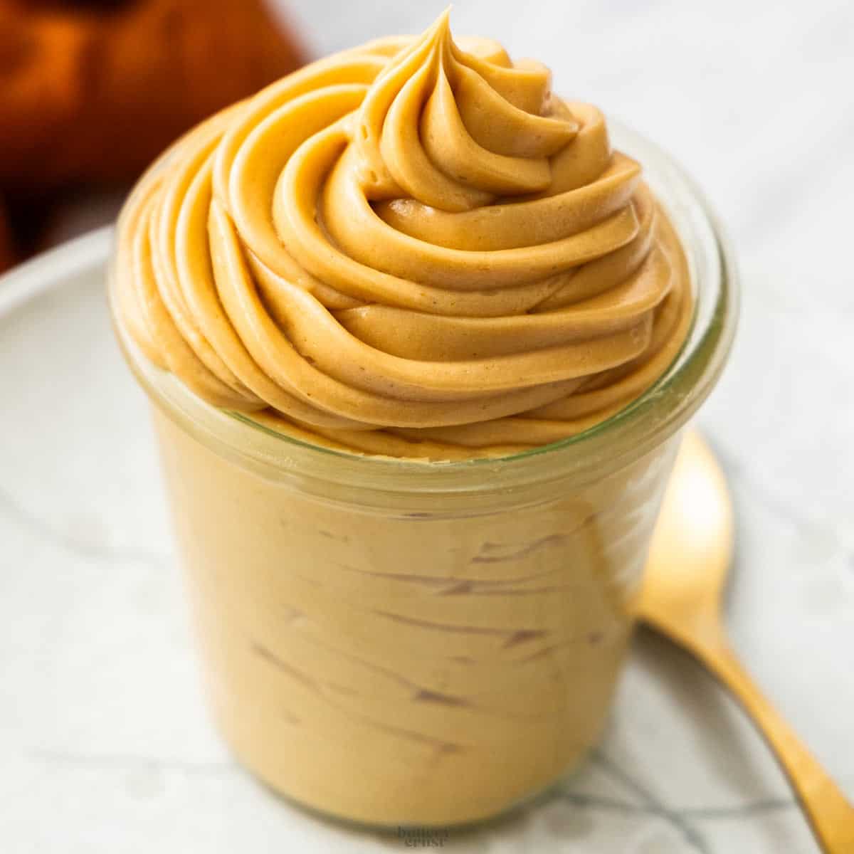 Praline cream piped into a glass jar in a big swirl.