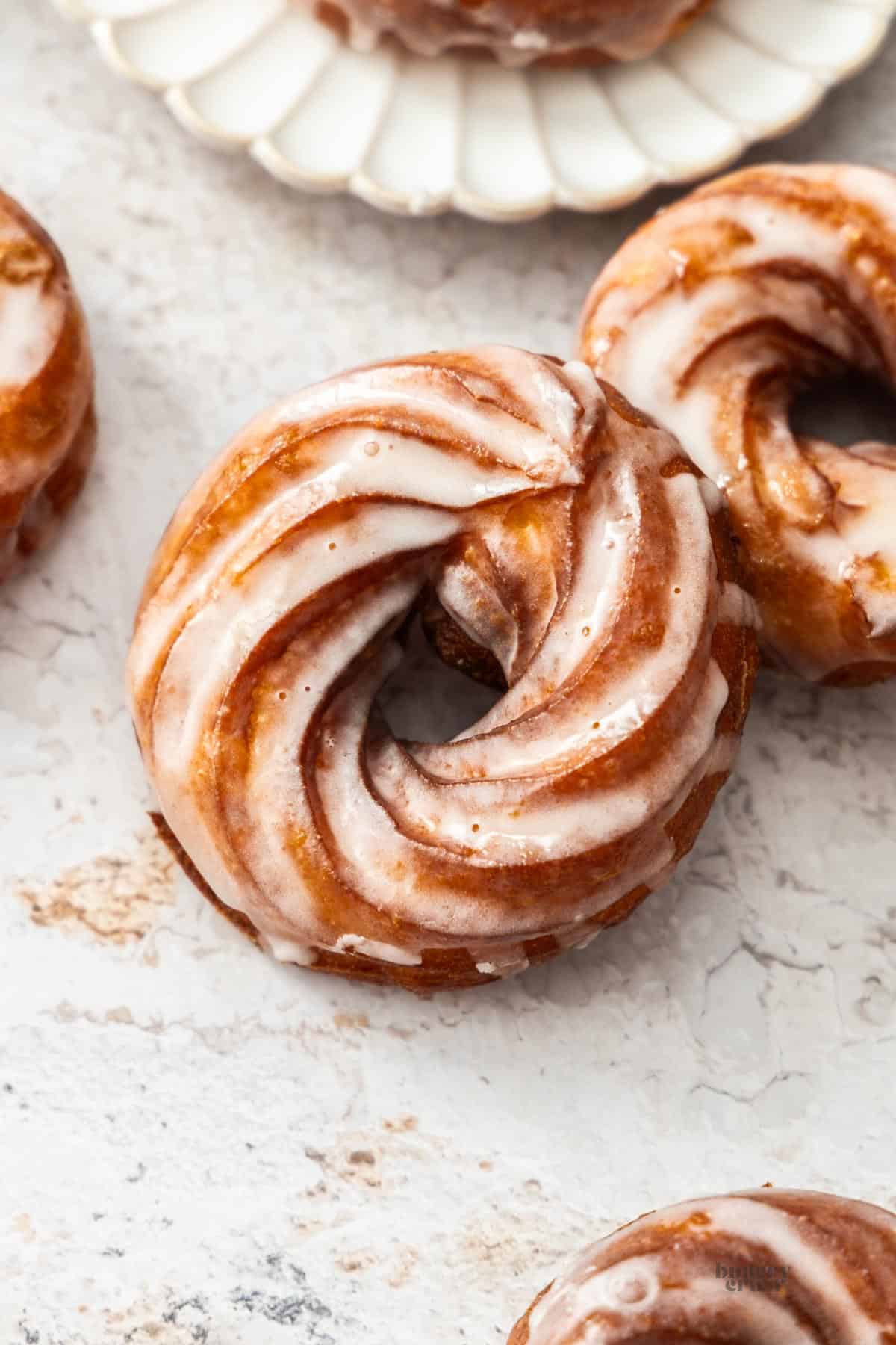 Five French crullers on a painted board.
