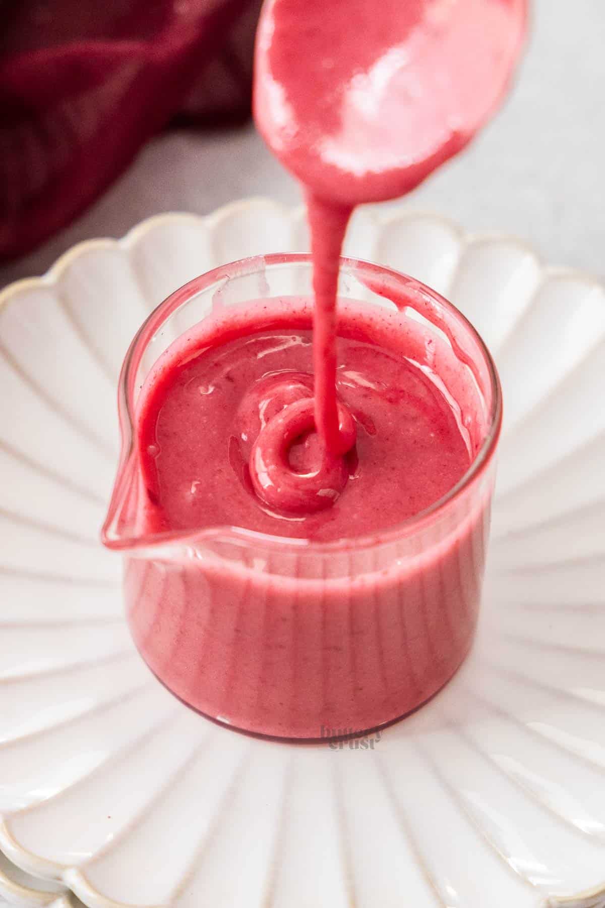 Blackberry glaze being drizzled into a glass jar.