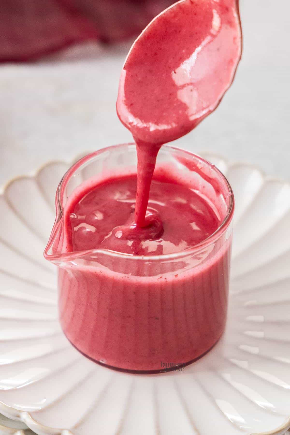 Blackberry glaze being drizzled into a small glass jug.