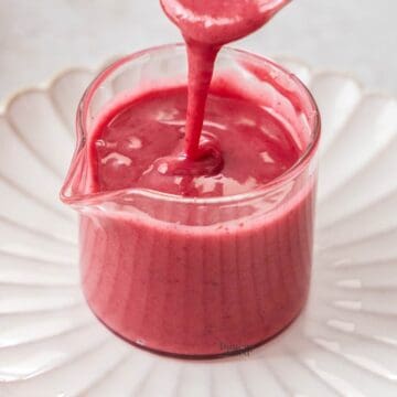 Blackberry glaze being drizzled into a small glass jug.