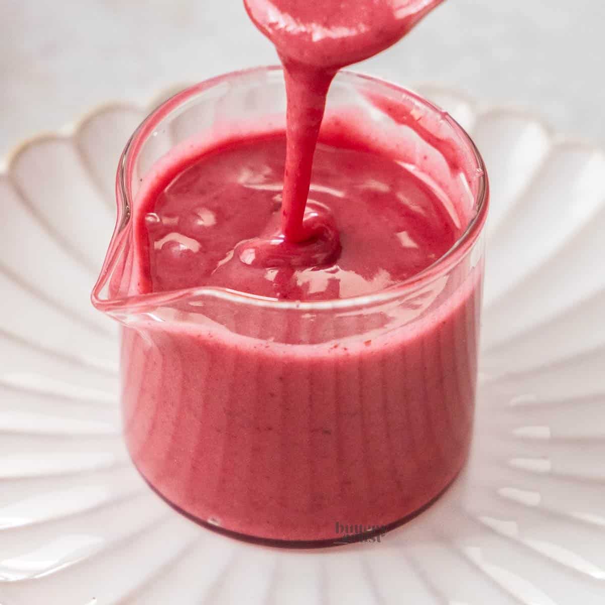 Blackberry glaze being drizzled into a small glass jug.