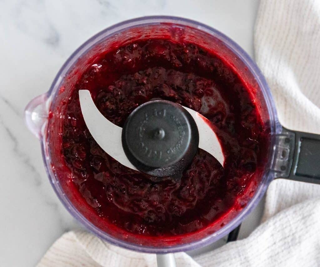 Blackberries being pureed in a small food processor.