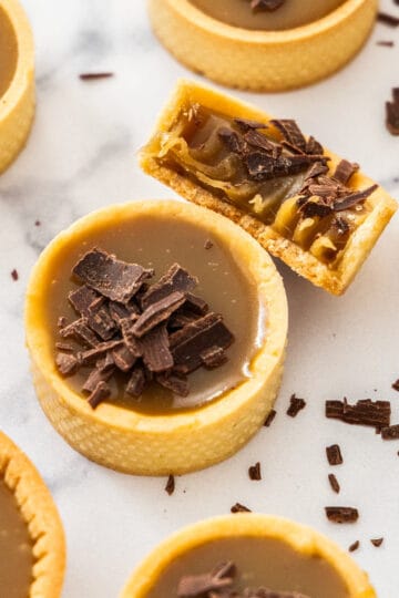 Top down view of a butterscotch tartlet with one broken open to show the butterscotch texture.