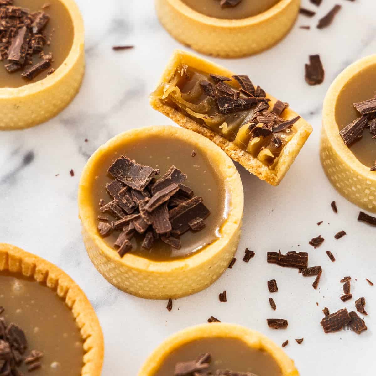 Top down view of a butterscotch tartlet with one broken open to show the butterscotch texture.