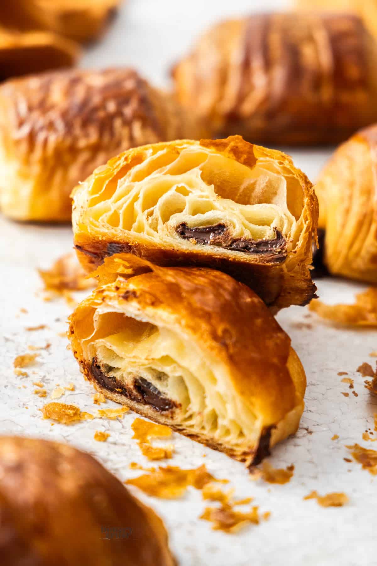 A chocolate croissant cut in half to show the holes inside.