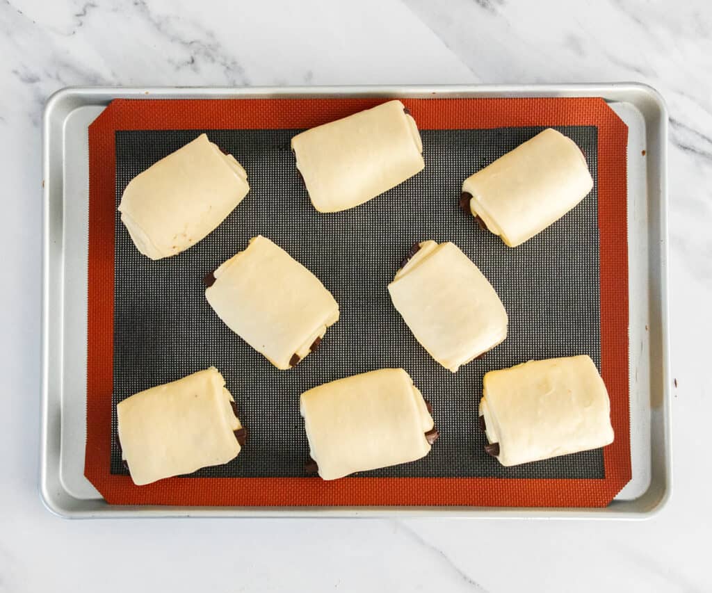 The eight rolls puffed up on a baking tray.