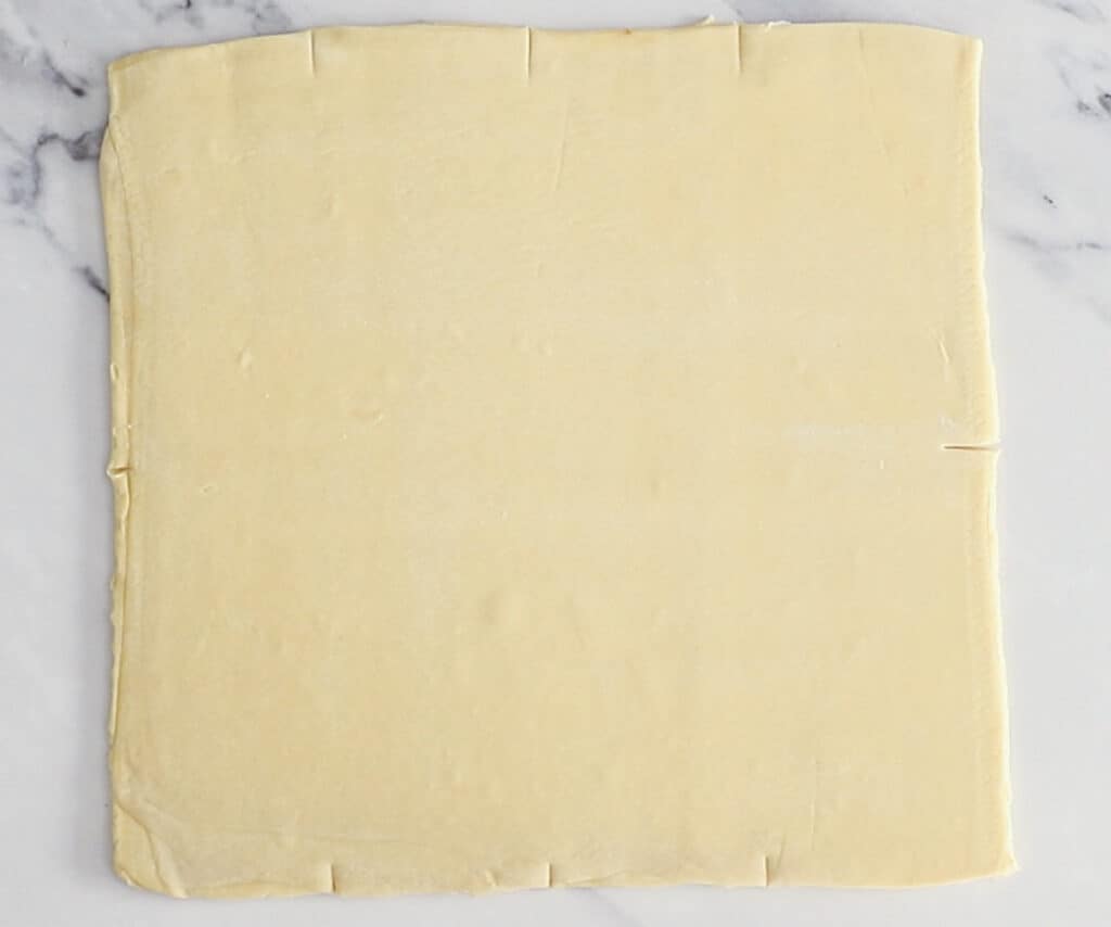 The dough rolled out into a square with markings on it for cutting.