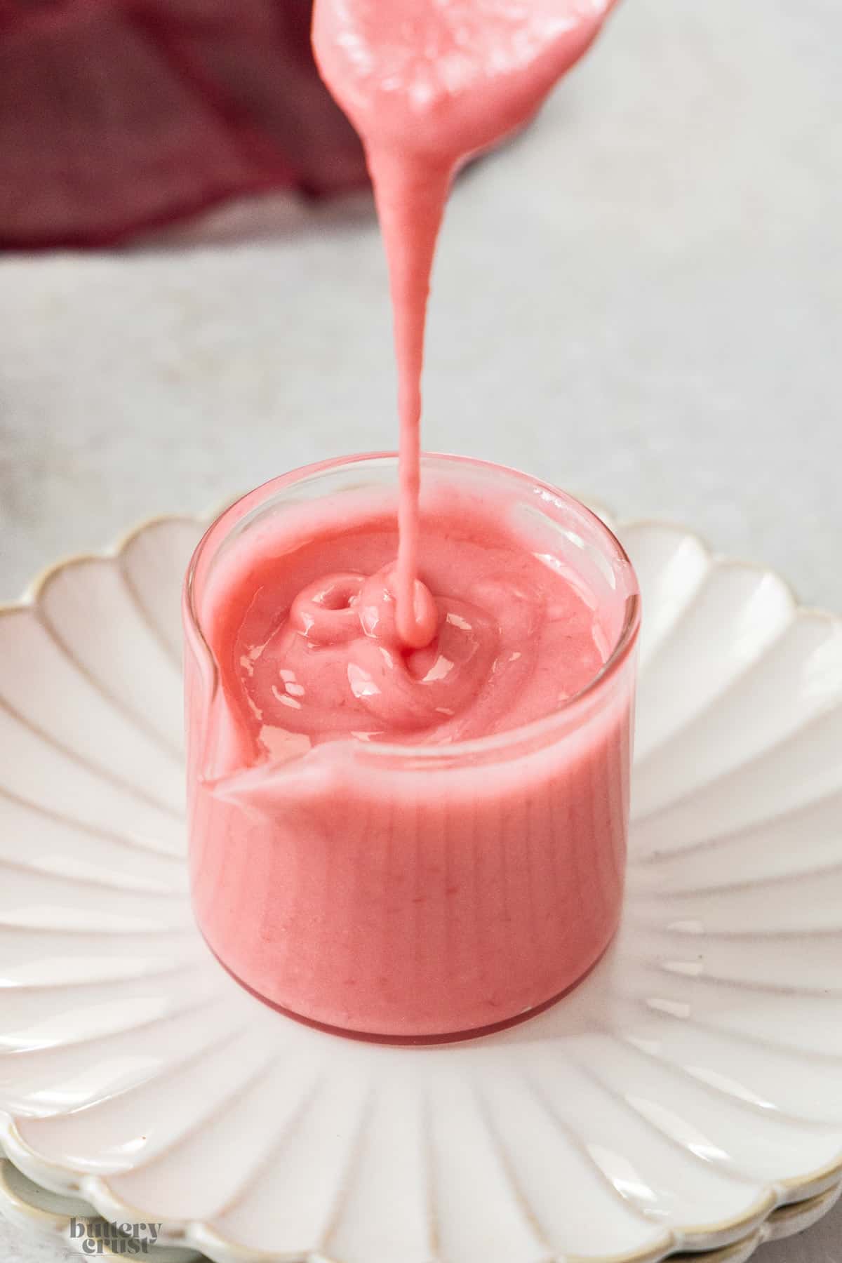 Raspberry icing being drizzled into a glass.