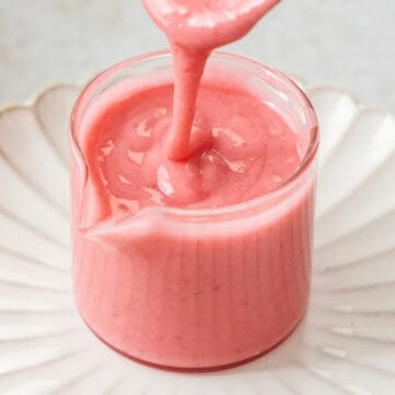 Closeup of raspberry icing in a glass jar.