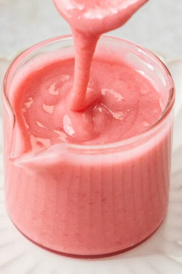 Closeup of raspberry icing in a glass jar.