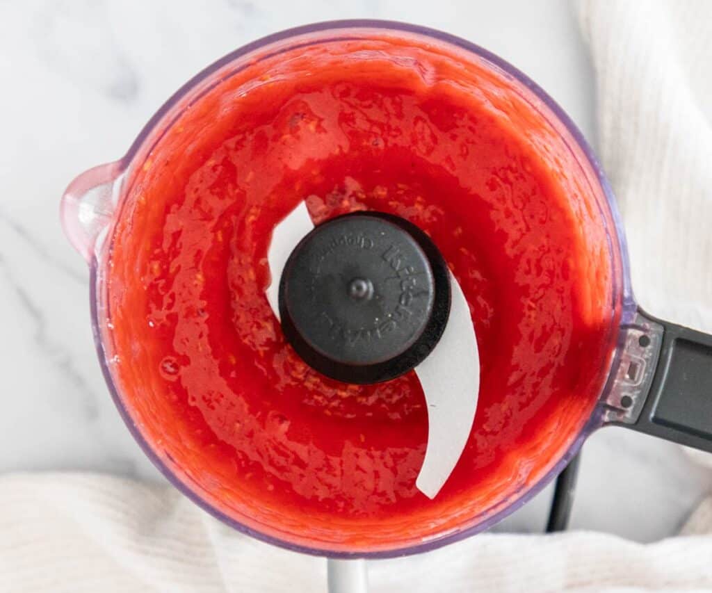 Pureed raspberries in a mini food processor.