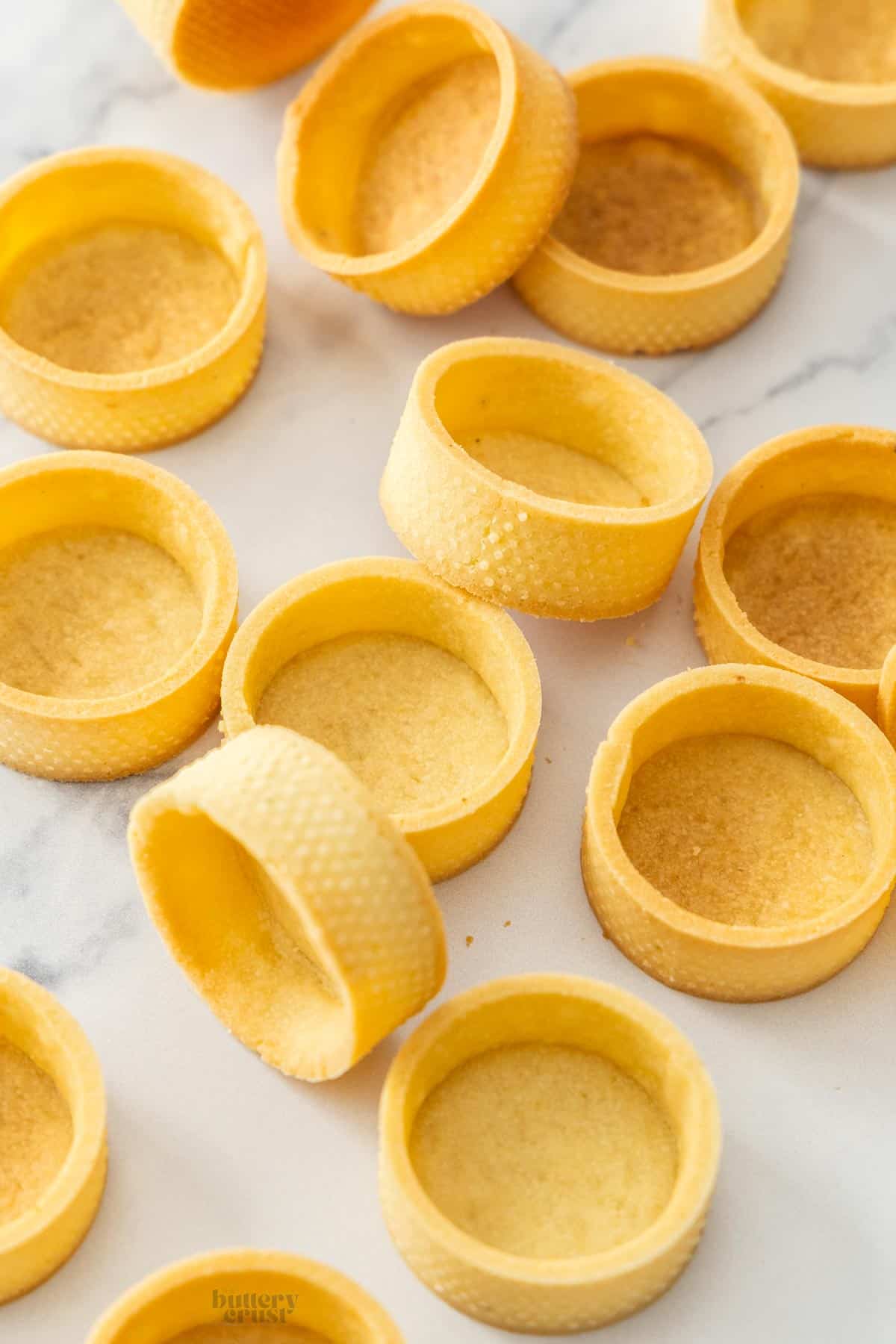 A pile of tart shells made in tart rings.
