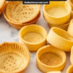 A pile of tartlet shells on a marble surface.