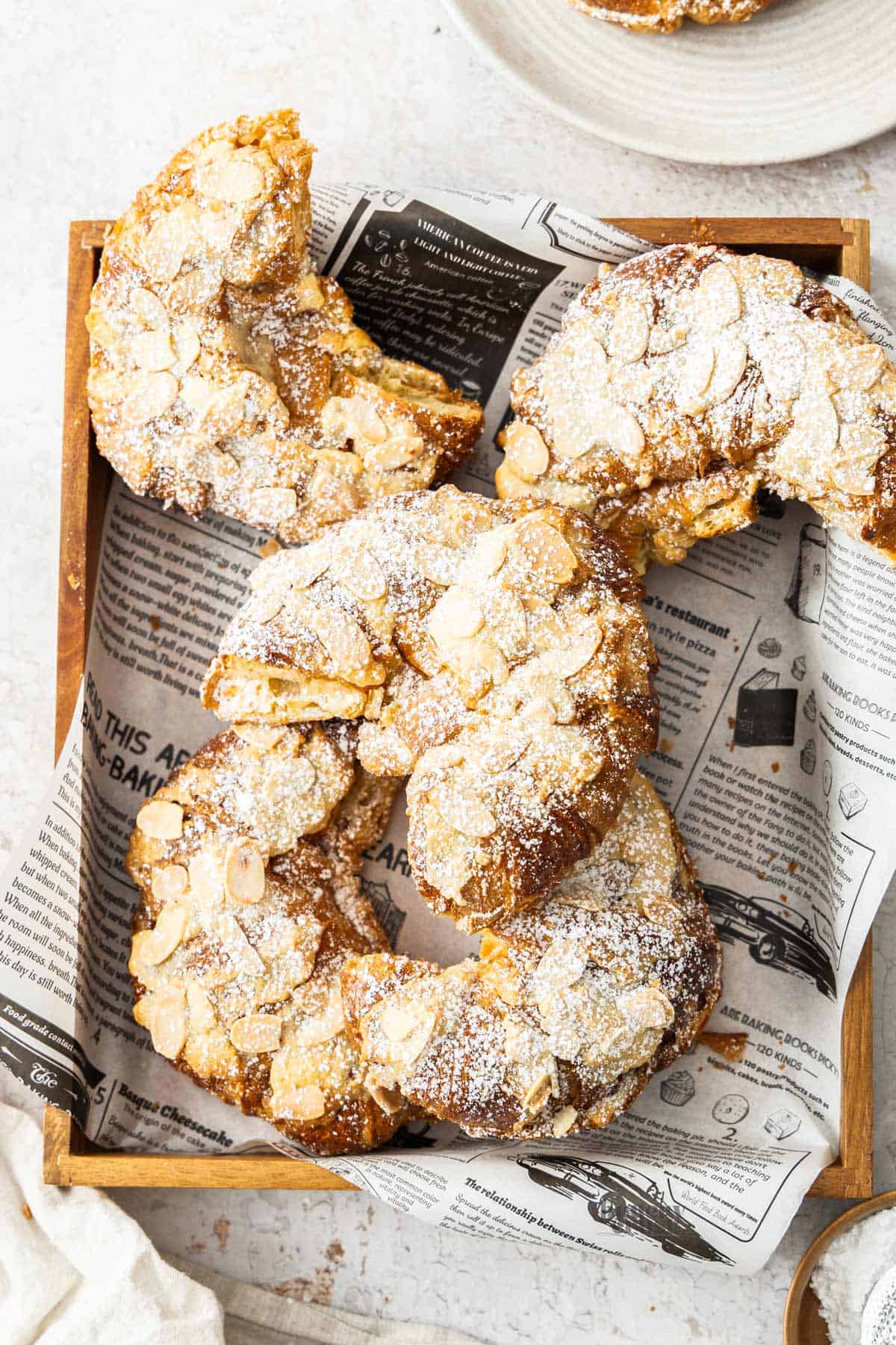 Top down view of five almond croissants on a wooden tray.
