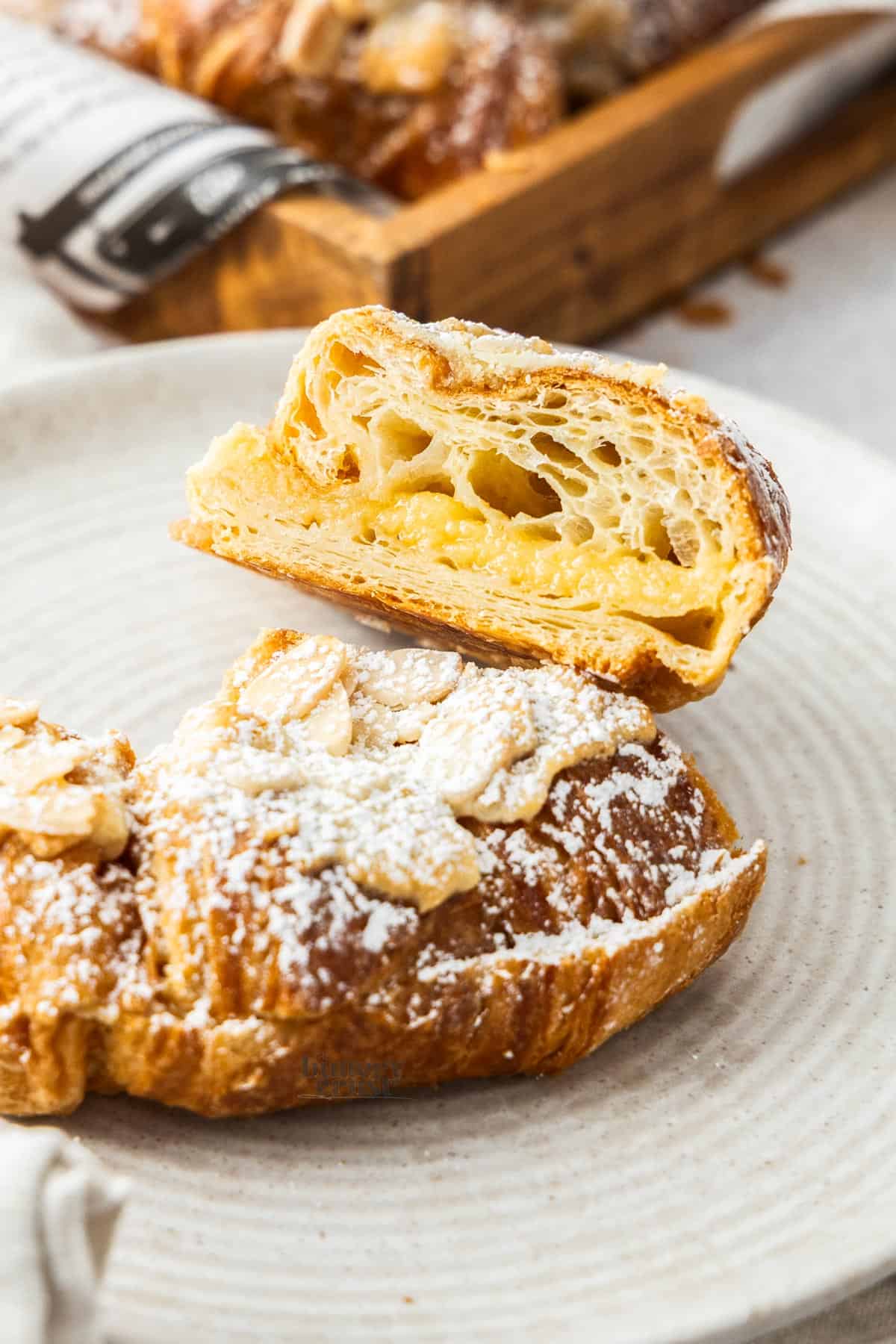 An almond filled croissant sliced in half on a plate.