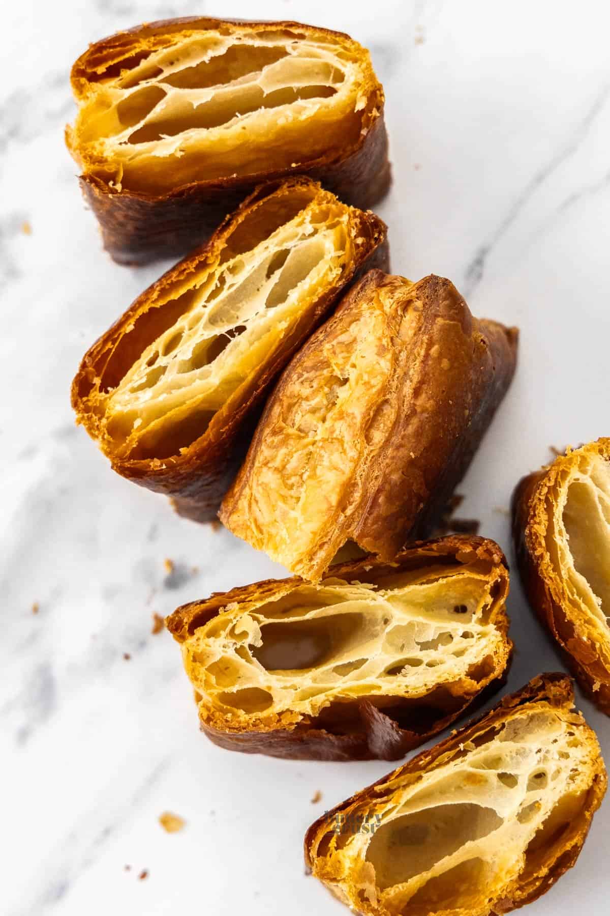 Six squares of puff pastry on a marble surface.