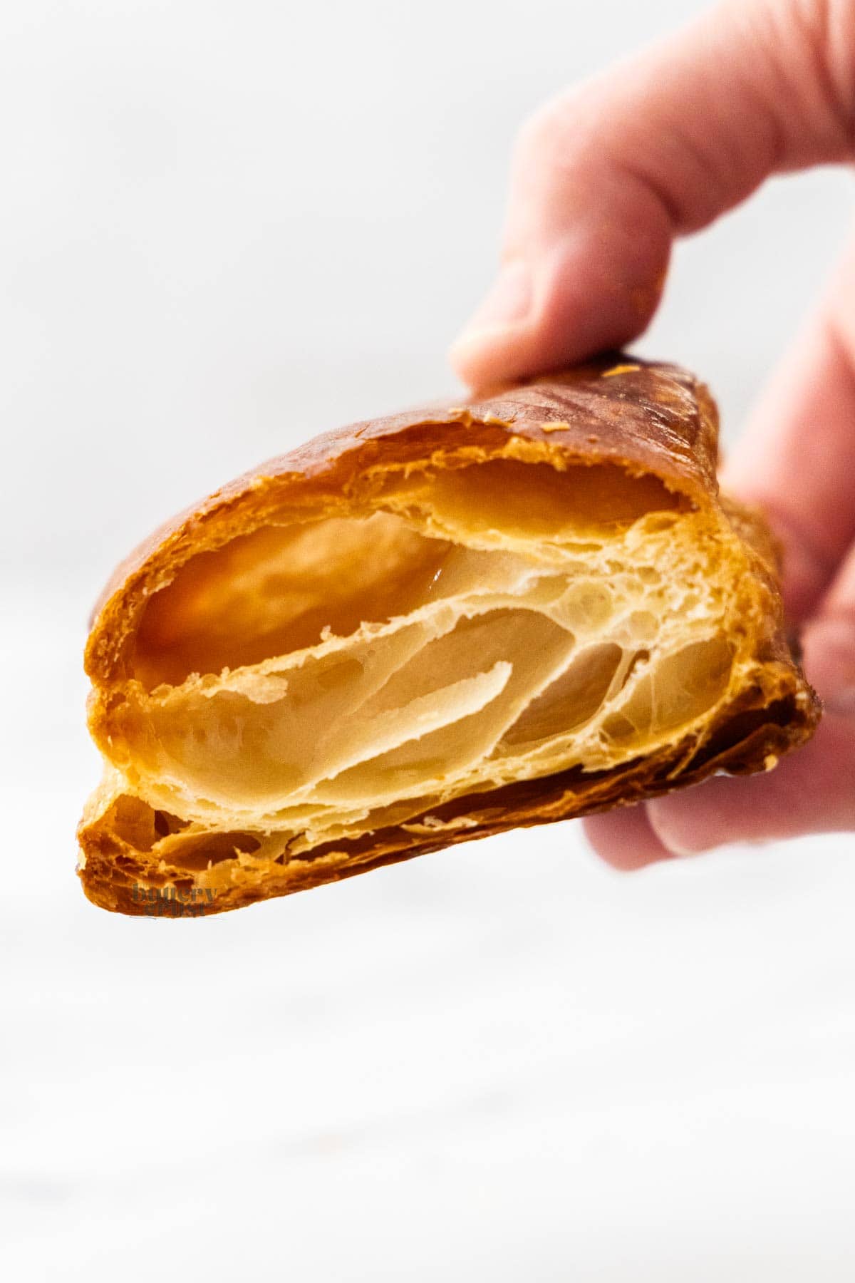 A hand holding a square of puff pastry.