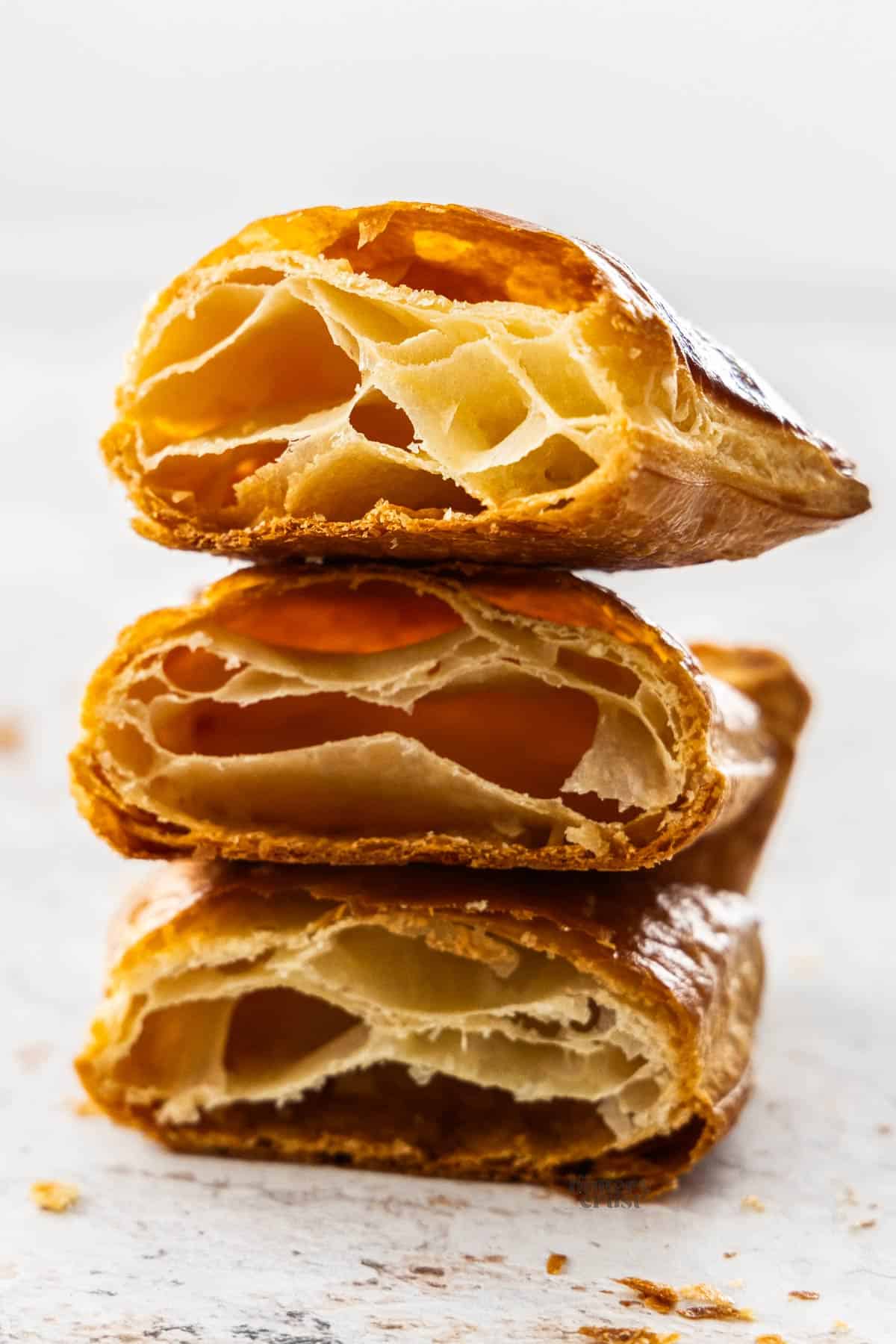 A stack of 3 pieces of baked rough puff pastry.